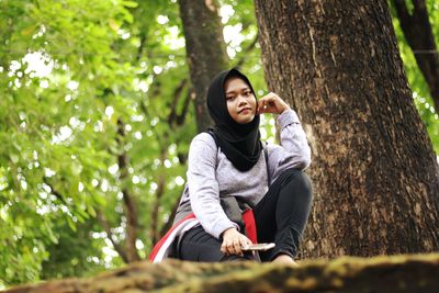 Woman sitting on tree trunk in forest