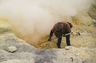 Miner digging sulfur at volcanic crater