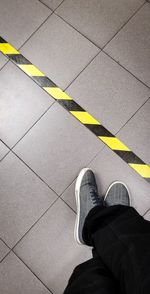 Low section of person standing on tiled floor