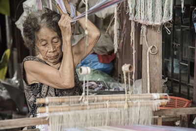 Senior woman weaving loom in factory