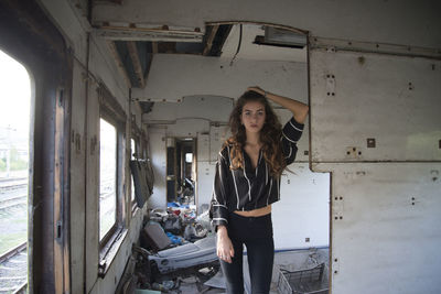 Portrait of young woman standing in abandoned train