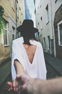 Cropped hand of man holding woman on street amidst buildings