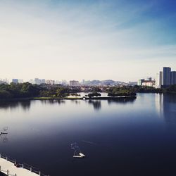 Scenic view of river by buildings against sky