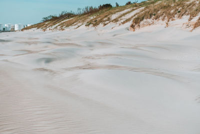 Scenic view of sand dune on beach against sky