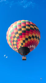 Low angle view of hot air balloons against clear blue sky