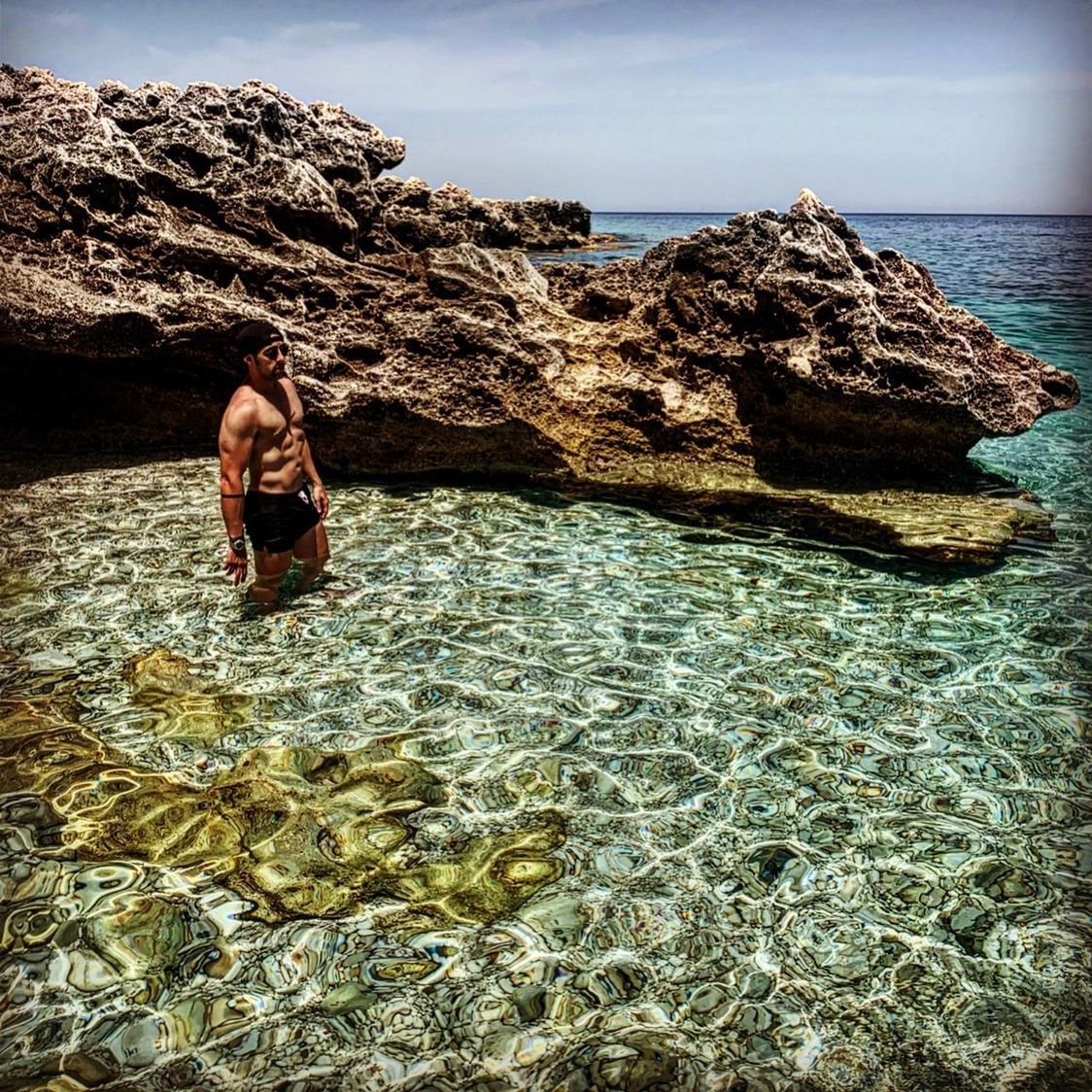 WOMAN SITTING ON ROCK AT SEA SHORE