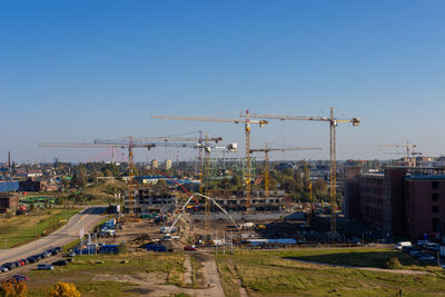 Cranes at construction site against sky in city