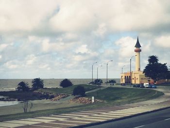 Lighthouse on sea against cloudy sky