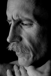 Close-up of thoughtful man against black background