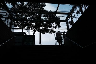 Low angle view of silhouette person walking on staircase against building