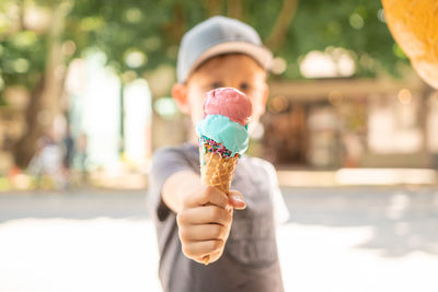 Boy holding ice cream cone while standing on road