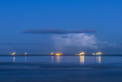 Boats sailing in sea against sky at night