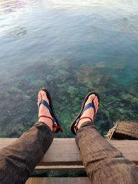 Low section of man sitting by lake