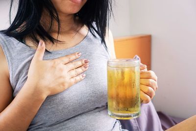 Asian woman having problem with gerd , acid reflux, after drinking beer in bed