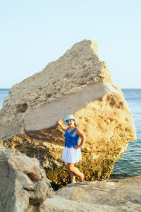 Rear view of woman standing on rock against sky