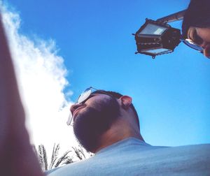 Low angle view of man photographing against sky