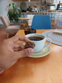 Cropped hand of person holding coffee on table