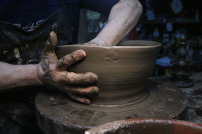 Midsection of man making pottery in workshop