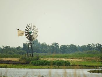 American-style windmill on lakeshore against clear sky