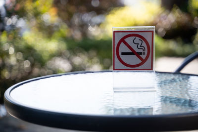 Close-up of no smoking sign on glass table at sidewalk cafe