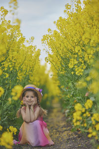 Young woman standing amidst yellow flowering plants on field