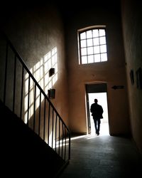 Rear view of silhouette man standing by door