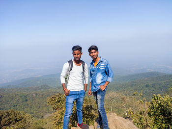 Portrait of young man standing on mountain against sky