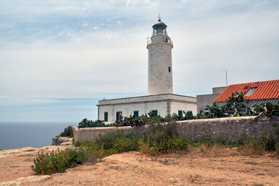 Lighthouse by sea against sky