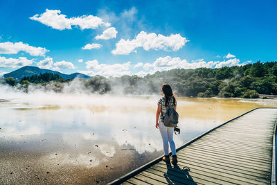 Rear view of woman standing on mountain against sky