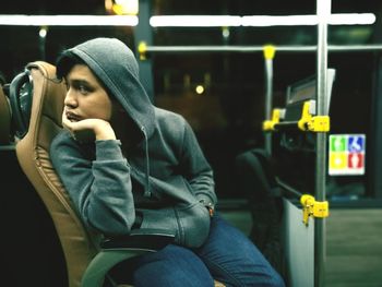 Bored young man with hands in pockets sitting on bus seat