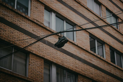 Low angle view of shoes hanging on cable against building