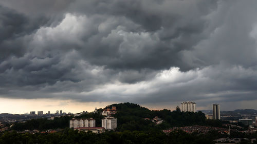 Buildings in city against storm clouds