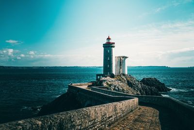 Lighthouse by sea against sky