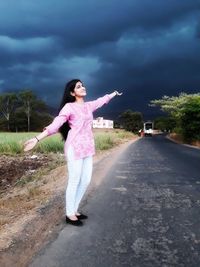 Full length of woman standing on road against sky