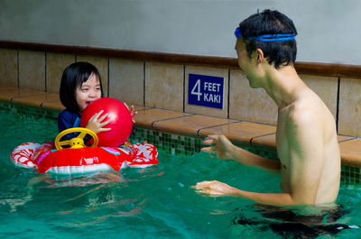 Father playing with daughter in swimming pool