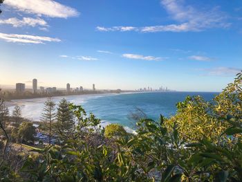 Scenic view of sea by city buildings against sky