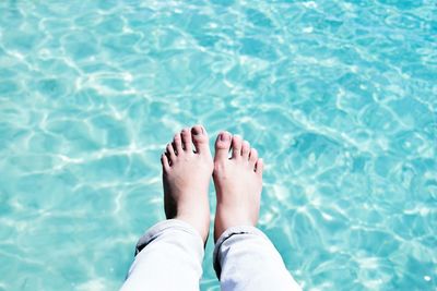 Low section of woman relaxing in swimming pool