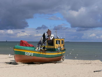 Boat moored on beach against sky