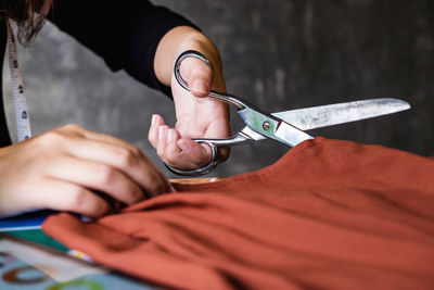 Midsection of fashion designer cutting clothes