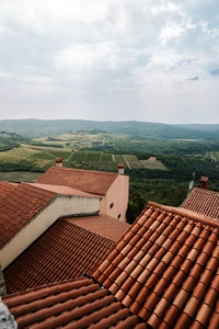 Scenic view of agricultural field against sky with rooftops