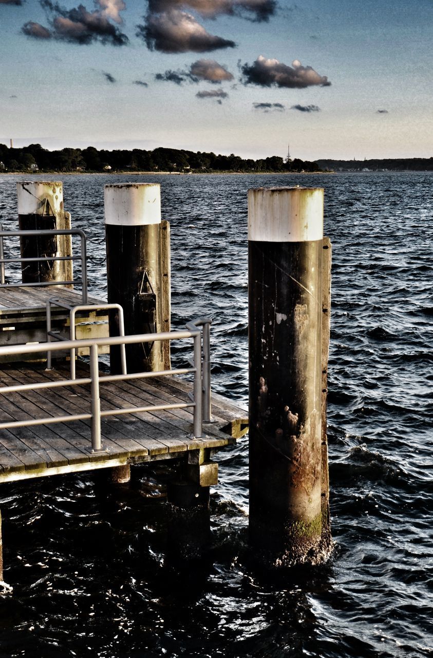 WOODEN POST ON SEA AGAINST SKY