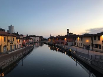 Canal amidst buildings in city against sky during sunset