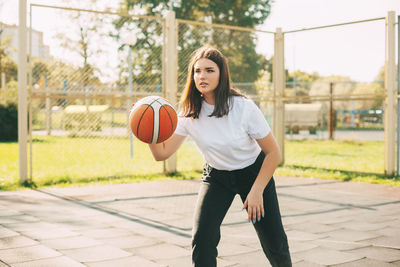 Teenage girl playing basketball in court