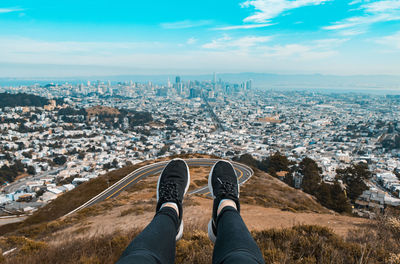 Low section of man over cityscape against sky