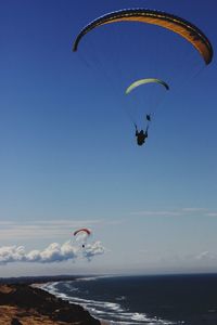 People paragliding over sea against clear sky