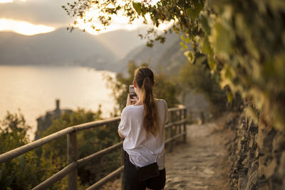 Full length of woman standing by railing against sky