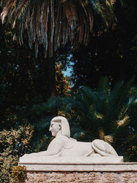 Statue against trees and plants in park