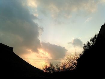 Low angle view of silhouette trees against cloudy sky