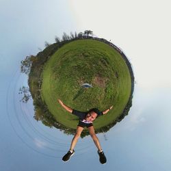 Little planet effect of man lying on field against sky