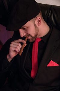 Close-up of man smoking cigar while sitting on sofa at home